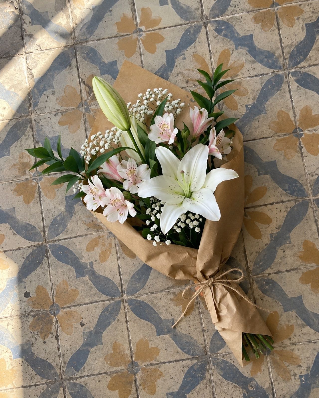Detall: 2 lilium blancos, 3 alstroemerias, paniculata y verde, en papel kraft