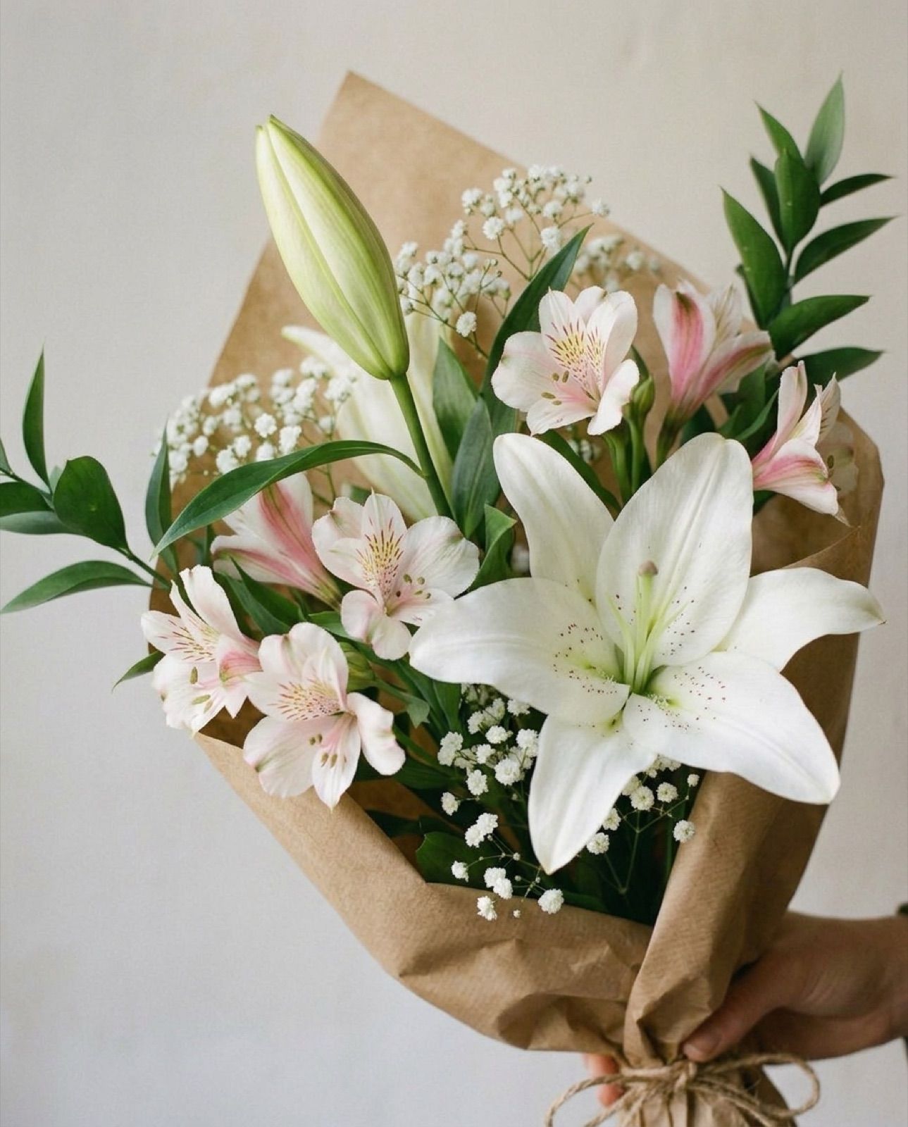Detall: 2 lilium blancos, 3 alstroemerias, paniculata y verde, en papel kraft